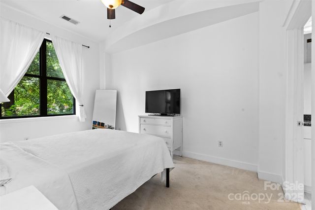 a bedroom with a bed a flat screen tv and a window