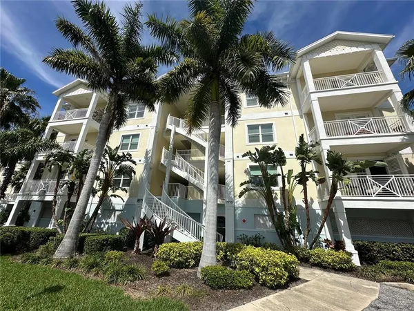 a front view of a multi story residential apartment building with yard and parking