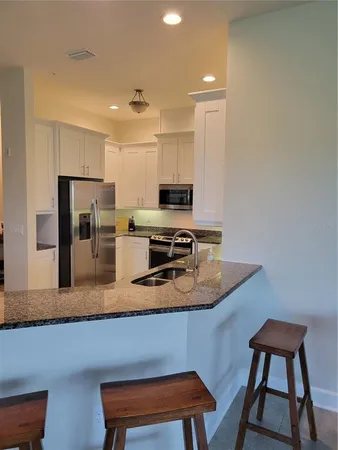 a kitchen with stainless steel appliances granite countertop a refrigerator a stove and a sink with wooden floor