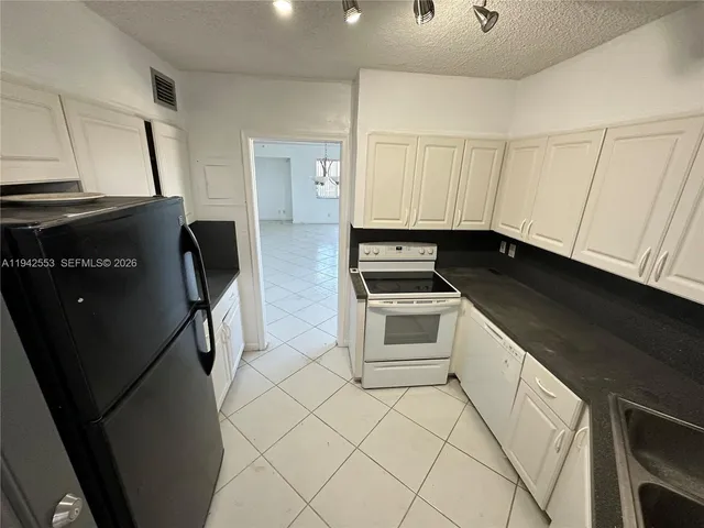 a kitchen with white cabinets and black appliances