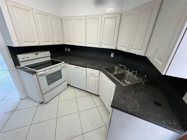 a kitchen with granite countertop white cabinets and appliances