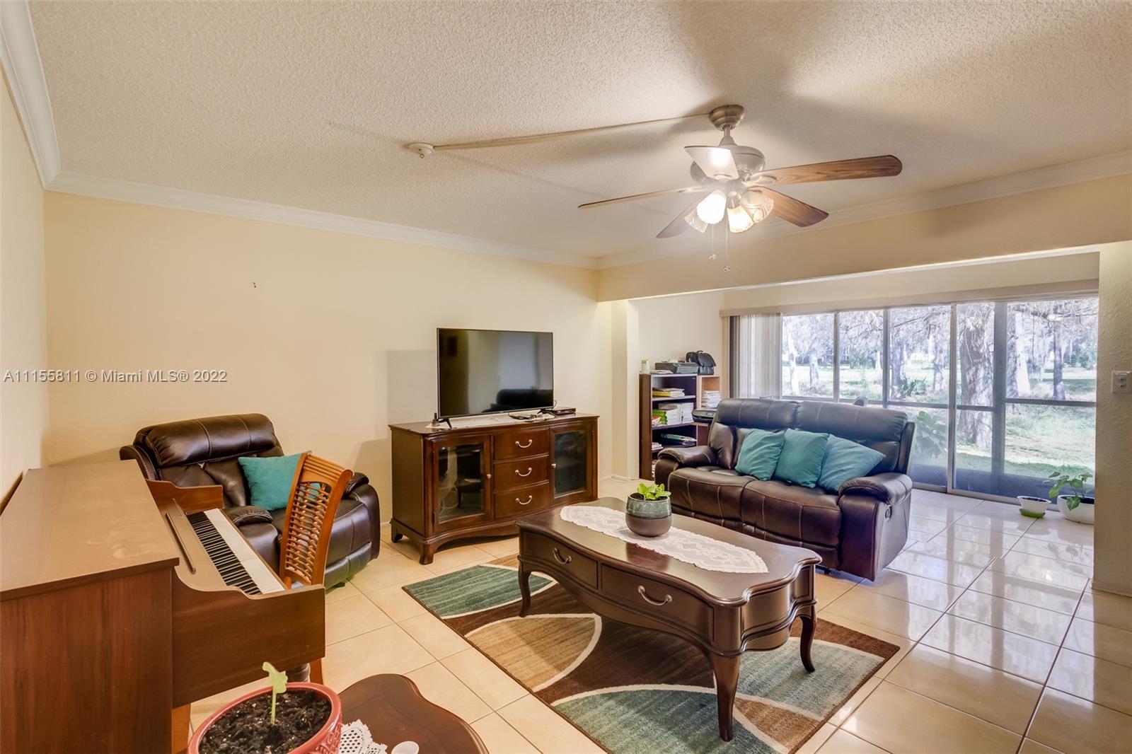 4106 Inverrary Drive, Unit 13C Lauderhill, FL 33319 - Photo 20 of 46 a living room with furniture a chandelier and a flat screen tv