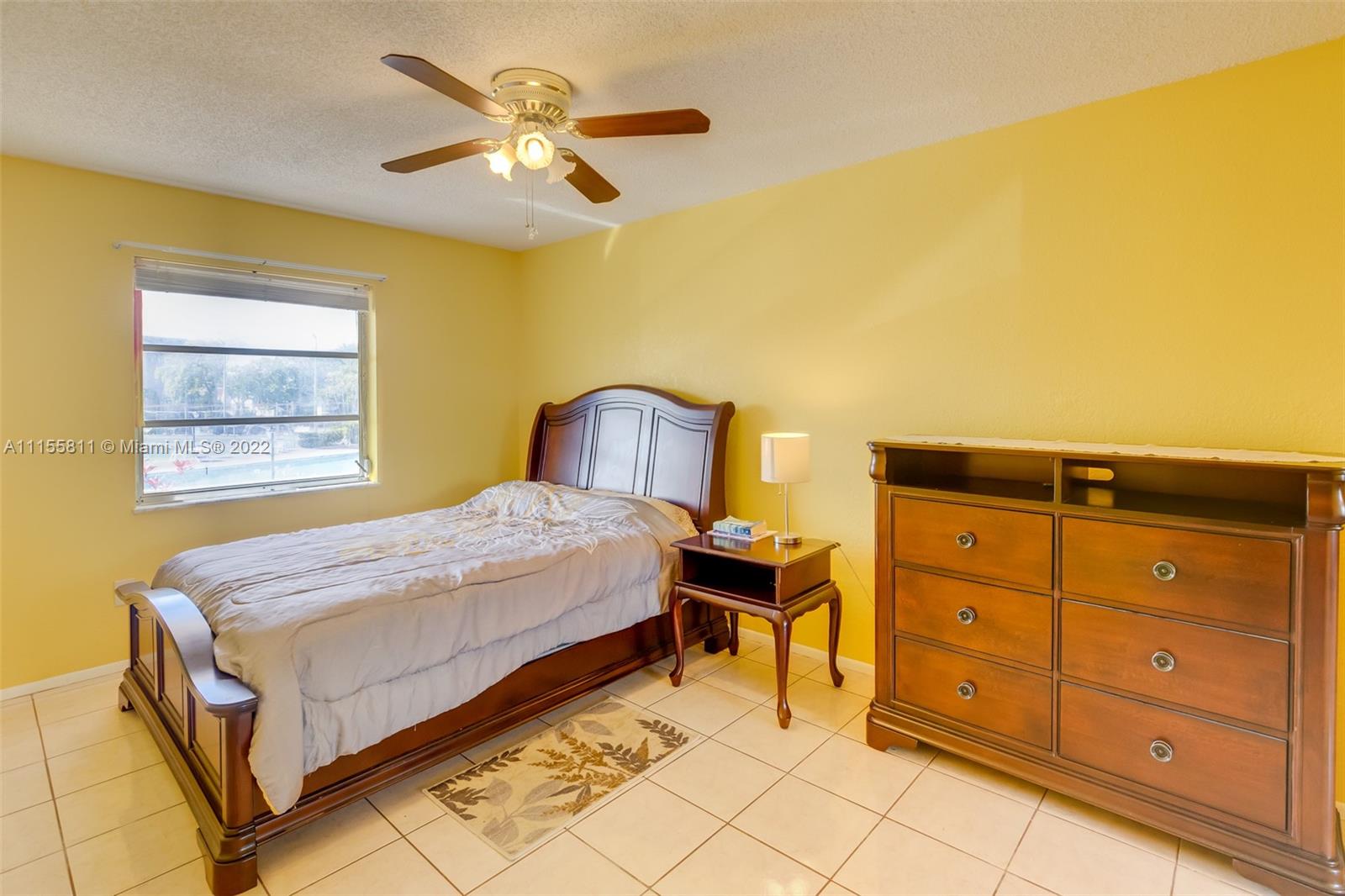 4106 Inverrary Drive, Unit 13C Lauderhill, FL 33319 - Photo 39 of 46 a bedroom with a bed and a chandelier