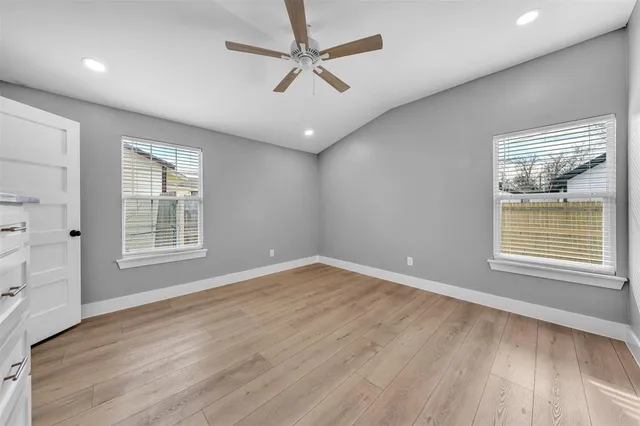 a view of an empty room with a window and wooden floor