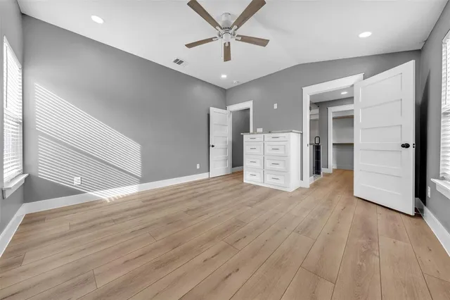 an empty room with wooden floor and ceiling fan