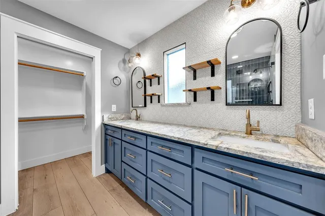 a bathroom with a granite countertop double vanity sink and two mirror