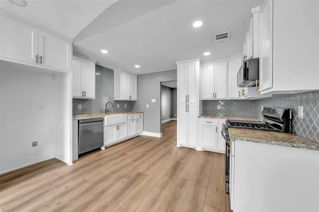 a kitchen with granite countertop a sink cabinets and stainless steel appliances