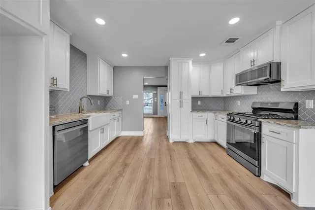 a large kitchen with stainless steel appliances granite countertop a lot of counter space and wooden floor