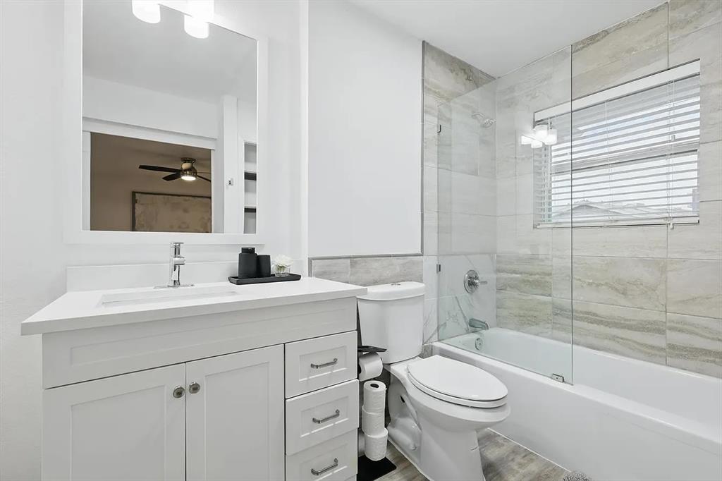 8083 Meadow Road, Unit 265 Dallas, TX 75231 - Photo 12 of 22 Bathroom featuring shower / bath combination with glass door, vanity, tile walls, and ceiling fan