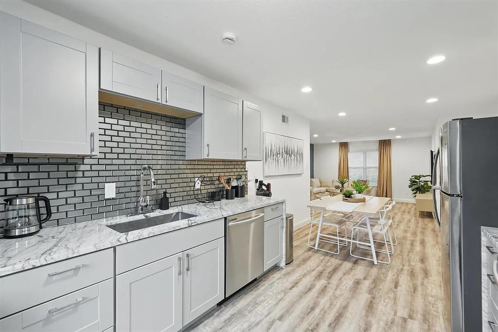 8083 Meadow Road, Unit 265 Dallas, TX 75231 - Photo 16 of 22 Kitchen featuring light stone countertops, appliances with stainless steel finishes, decorative backsplash, light wood-style floors, and recessed lighting