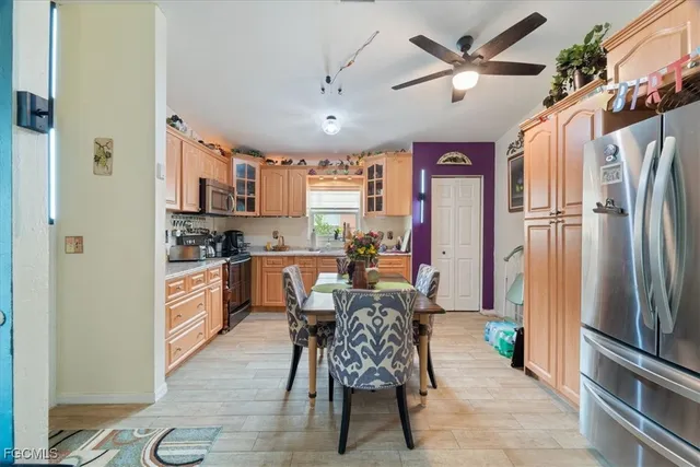 a kitchen with stainless steel appliances kitchen island granite countertop a refrigerator a stove a sink a dining table and chairs with the floor