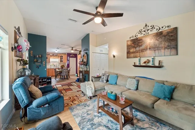 a living room with furniture a flat screen tv and a ceiling fan