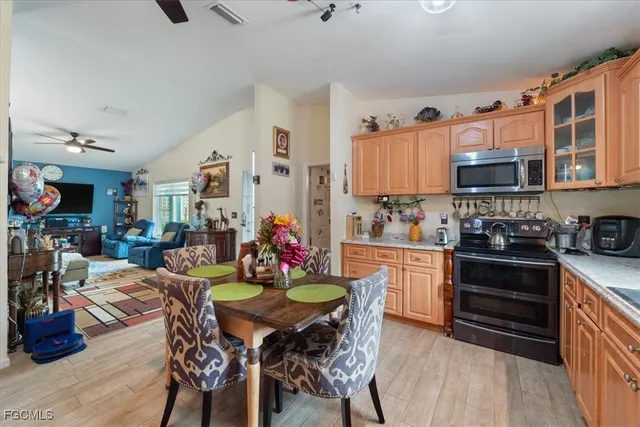 a kitchen with stainless steel appliances kitchen island granite countertop a dining table and chairs with wooden floor