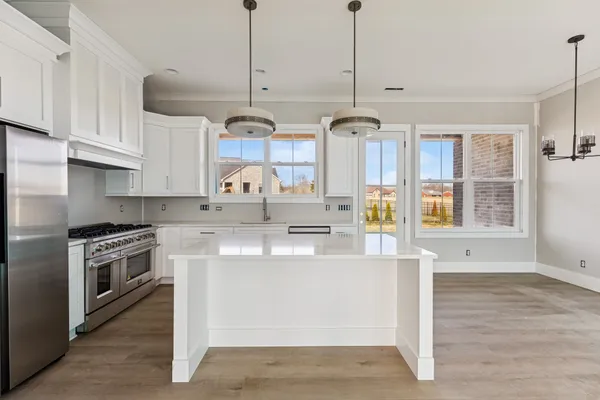 a kitchen with stainless steel appliances granite countertop a sink a stove and a wooden floor