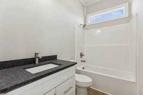 a bathroom with a granite countertop sink a toilet and bathtub