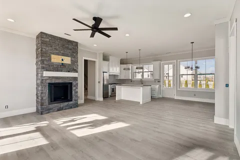 a view of a livingroom with a fireplace a ceiling fan and windows