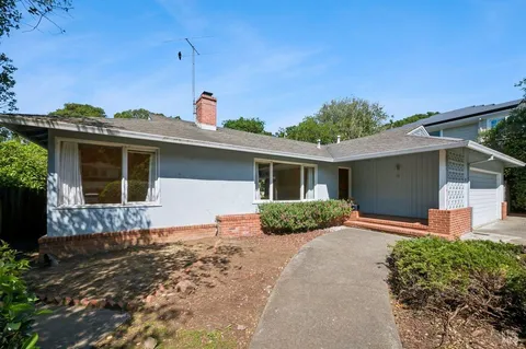 a front view of a house with a yard and potted plants