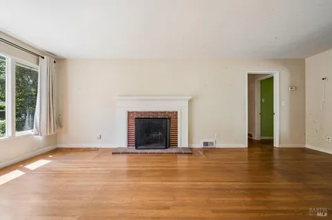 a view of an empty room with glass door and wooden floor