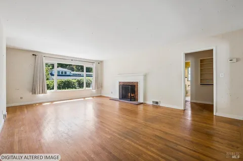 a view of empty room with wooden floor and fireplace