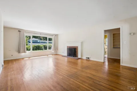 a view of empty room with wooden floor and fireplace