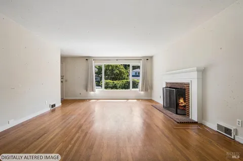 an empty room with wooden floor fireplace and windows