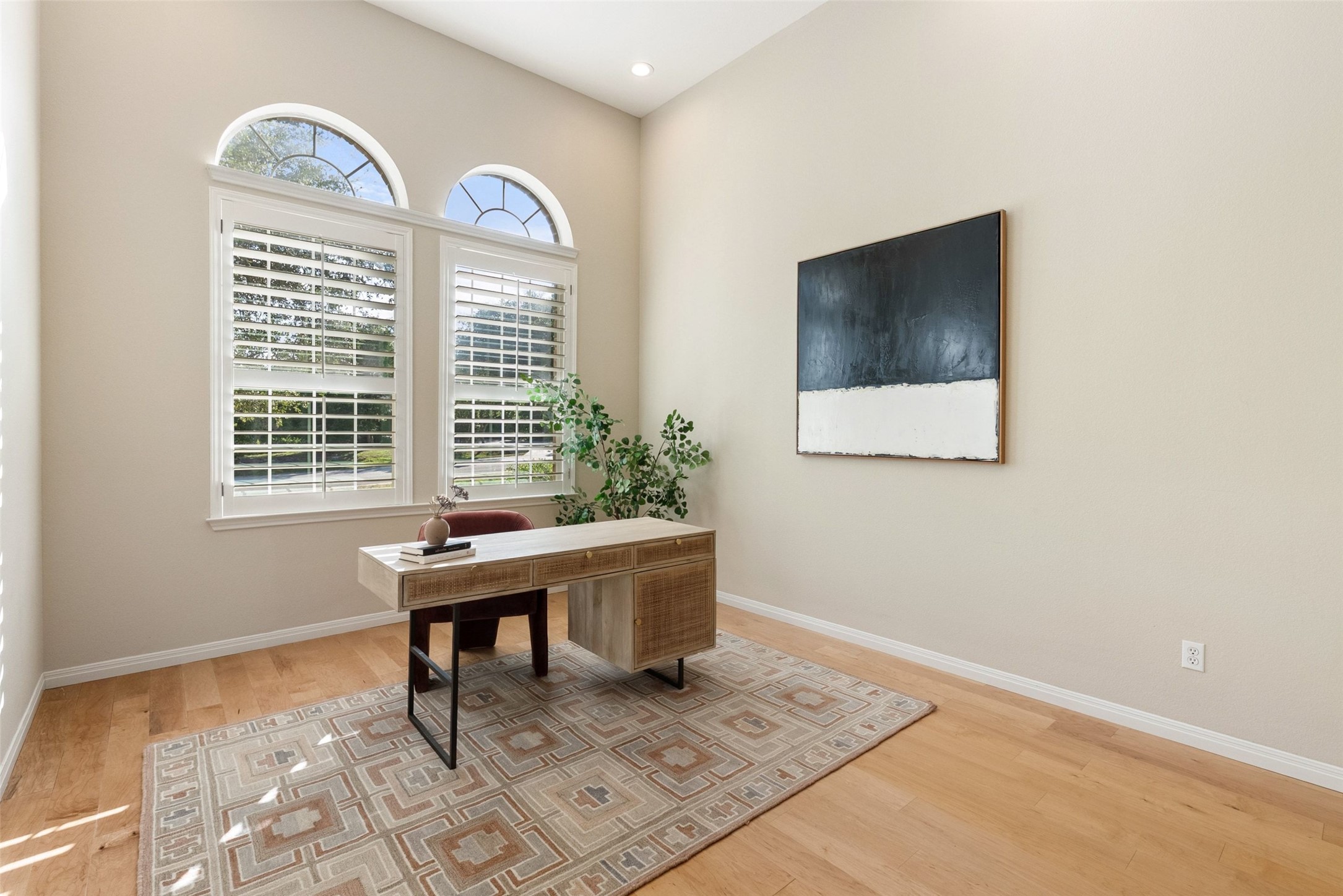 8215 Dark Ridge Cove Austin, TX 78737 - Photo 8 of 40 Natural light floods this expansive home office space featuring charming arched windows, hardwood floors, and a private half bath.