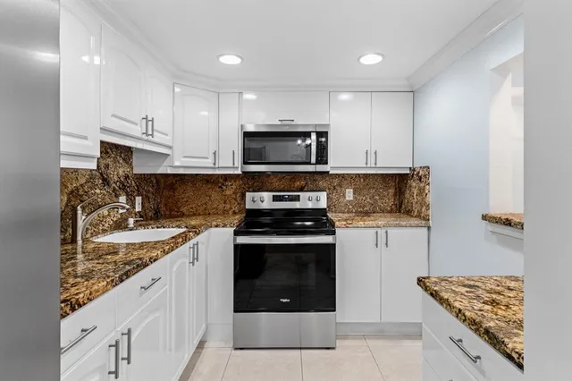 a kitchen with stainless steel appliances granite countertop a stove sink and cabinets