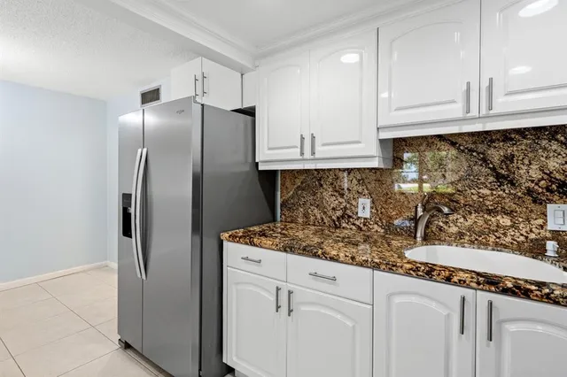 a kitchen with granite countertop a refrigerator and cabinets