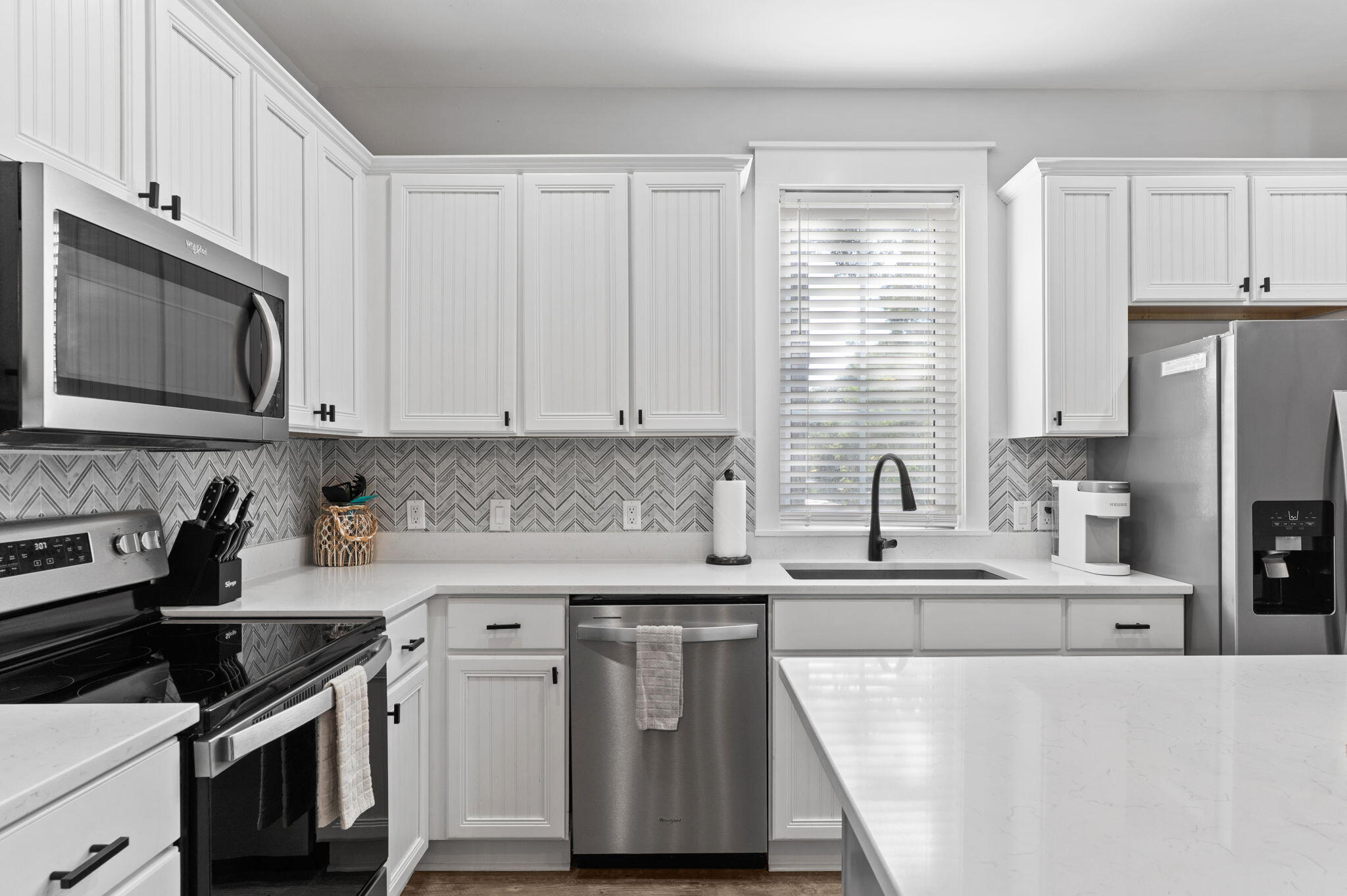 1352 Ravens Run West Miramar Beach, FL 32550 - Photo 16 of 50 a kitchen with stainless steel appliances granite countertop white cabinets a sink a stove a refrigerator and microwave with wooden floor