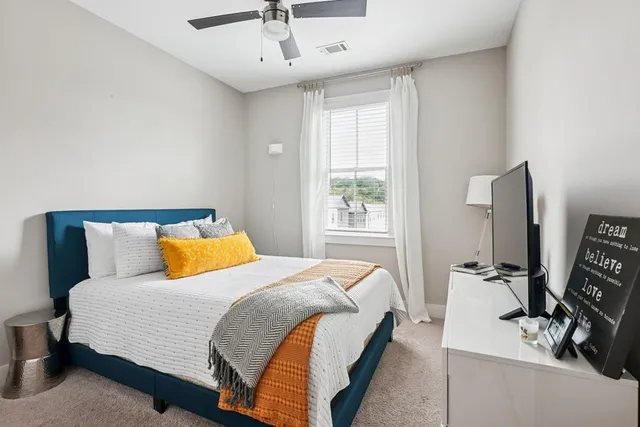 a bedroom with a bed and a flat tv screen on a dresser