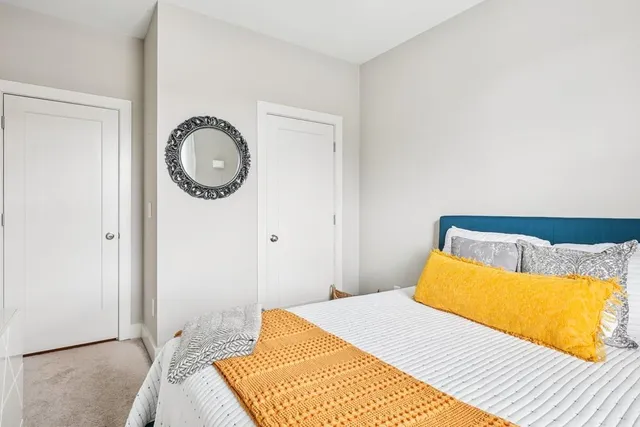 a bedroom with a bed and a lamp on dresser