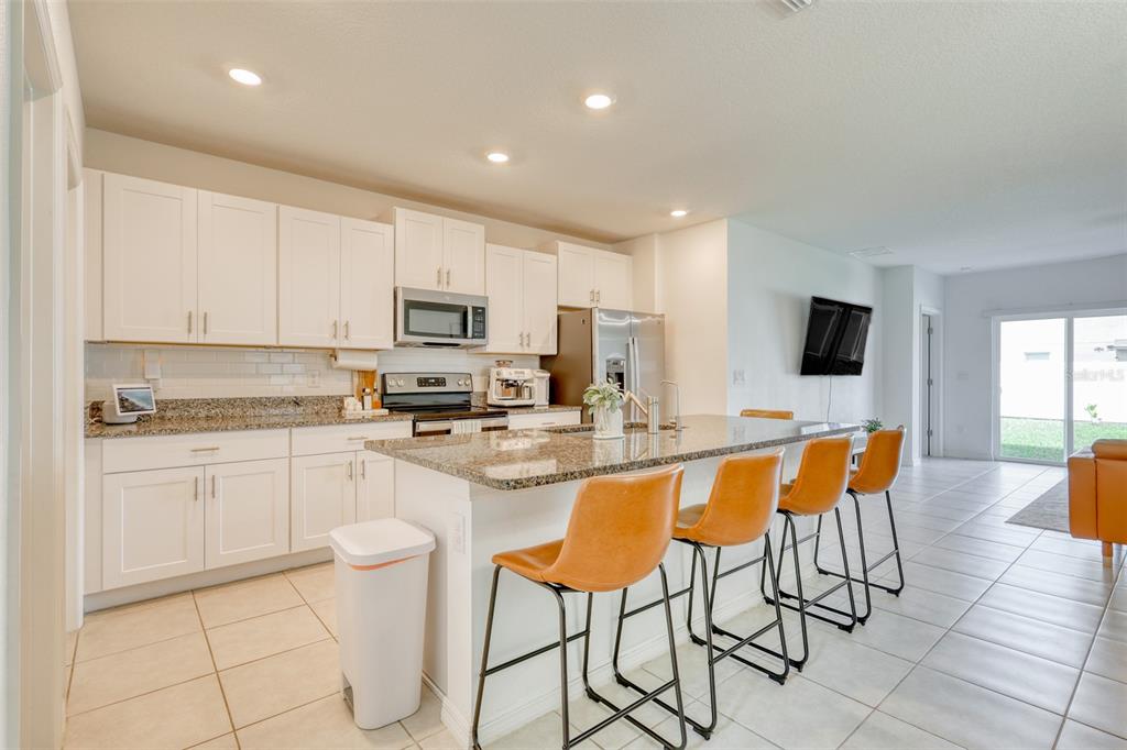 111 Rain Lily Ave Spring Hill Spring Hill, FL 34609 - Photo 37 of 60 a kitchen with stainless steel appliances granite countertop a stove a sink a microwave a dining table and chairs