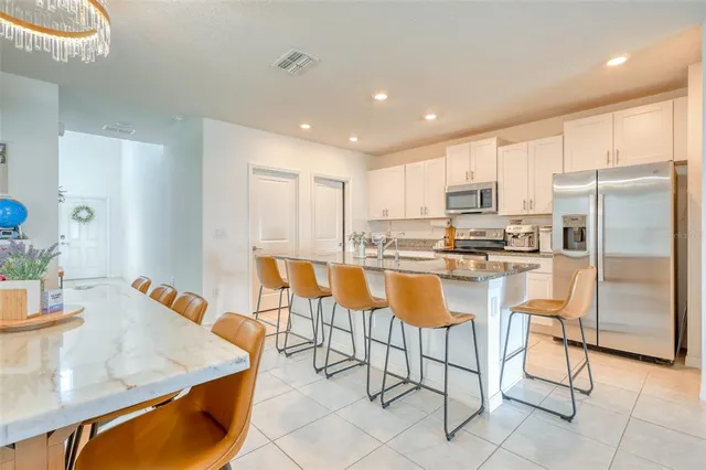 a kitchen with granite countertop a refrigerator a stove a sink a dining table and chairs