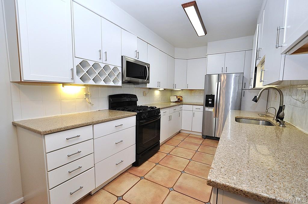 253 Garth Road, Unit 1S Scarsdale, NY 10583 - Photo 1 of 1 a kitchen with stainless steel appliances granite countertop a sink a stove a microwave a refrigerator a counter top space and cabinets