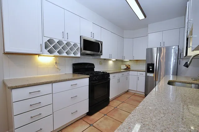 a kitchen with stainless steel appliances a refrigerator sink and white cabinets