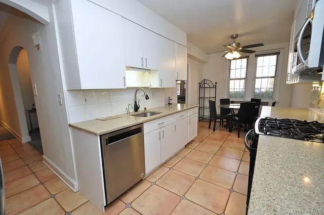 a kitchen with a sink a stove and white cabinets