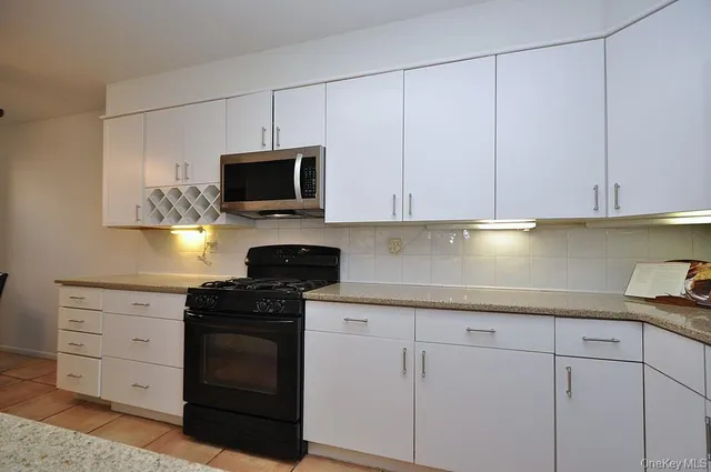 a kitchen with white cabinets and black appliances