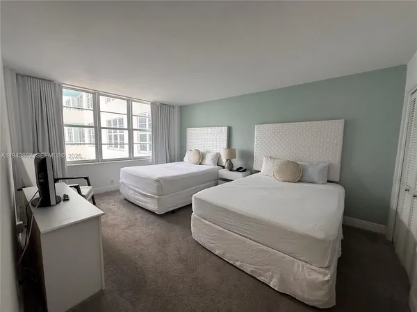 a spacious bedroom with two beds and large window