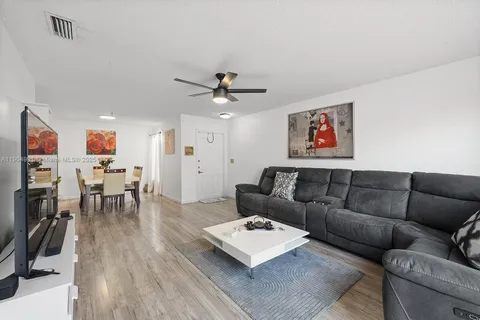 a living room with furniture kitchen view and a wooden floor