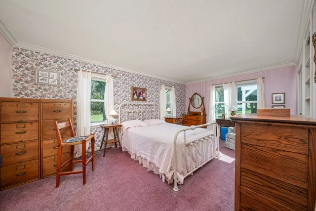 a bedroom with a bed a dresser next to a window