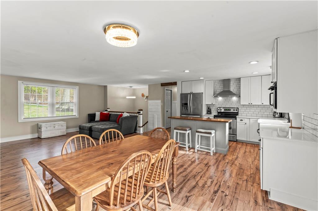359 Hunting Creek Road Canonsburg, PA 15317 - Photo 12 of 39 a kitchen with stainless steel appliances granite countertop a stove top oven a sink a dining table and chairs with wooden floor