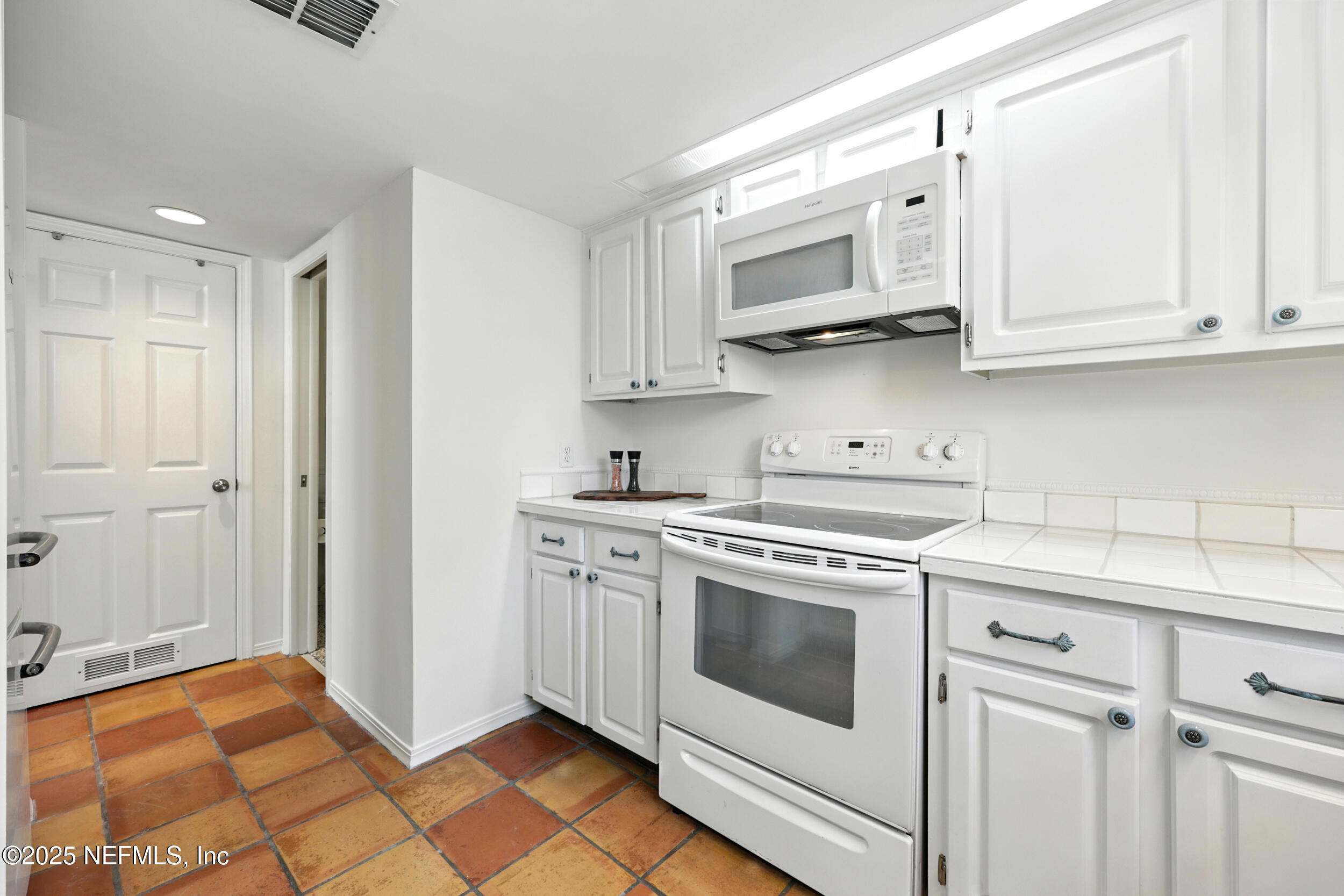 600 First Street Neptune Beach, FL 32266 - Photo 22 of 80 a kitchen with white cabinets and white appliances