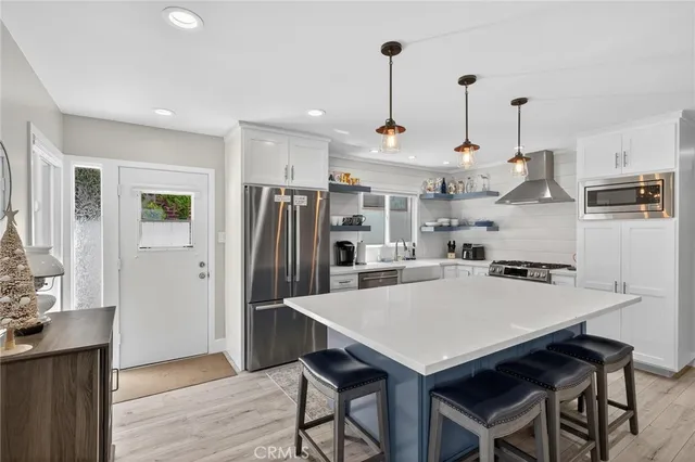 a kitchen with stainless steel appliances granite countertop a stove a refrigerator a kitchen island a sink and a refrigerator