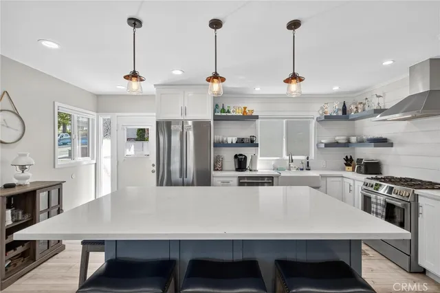 a kitchen with stainless steel appliances granite countertop a sink a stove a refrigerator cabinets and chairs