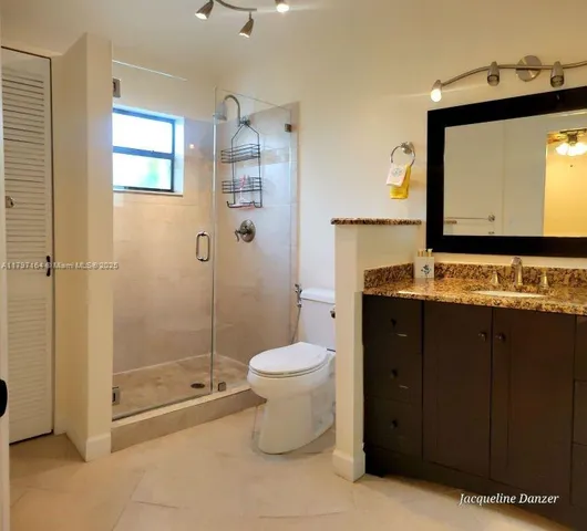 a bathroom with a granite countertop toilet sink and mirror