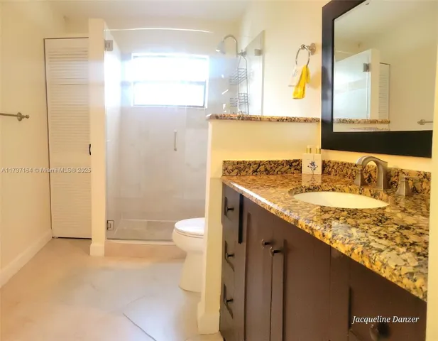 a bathroom with a granite countertop sink a toilet and shower