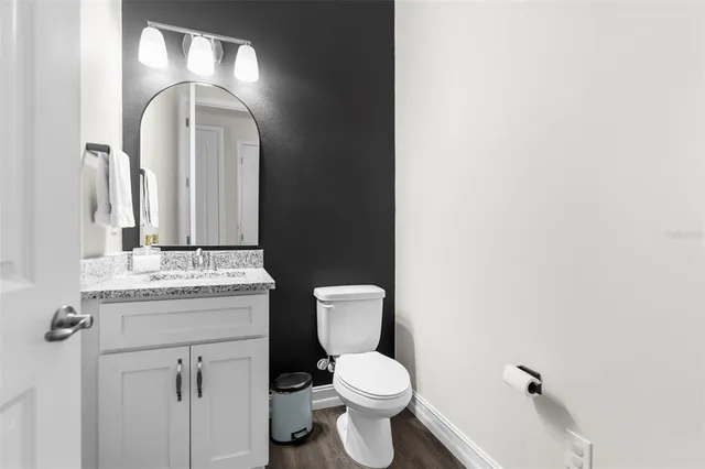 a bathroom with a granite countertop toilet sink and mirror