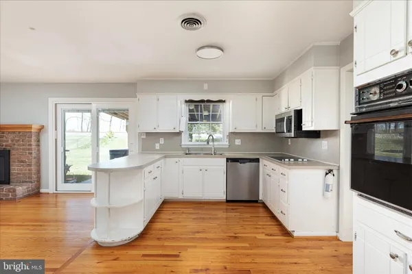 a large kitchen with granite countertop a stove top oven a sink a counter space and cabinets