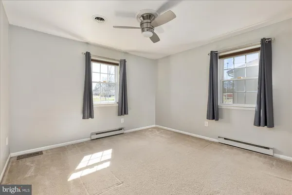 an empty room with windows and ceiling fan