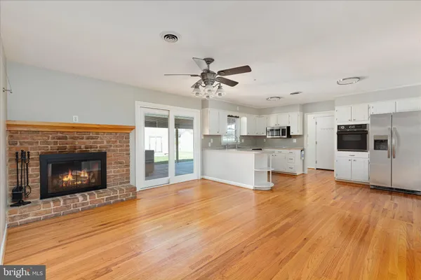 a living room with stainless steel appliances kitchen island a fireplace and a chandelier